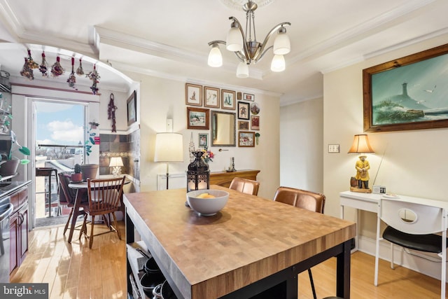 dining space featuring ornamental molding, light hardwood / wood-style floors, and a chandelier