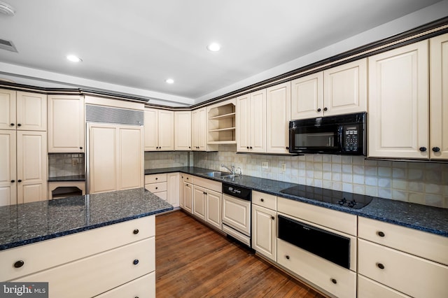 kitchen featuring sink, tasteful backsplash, dark hardwood / wood-style floors, dark stone counters, and black appliances