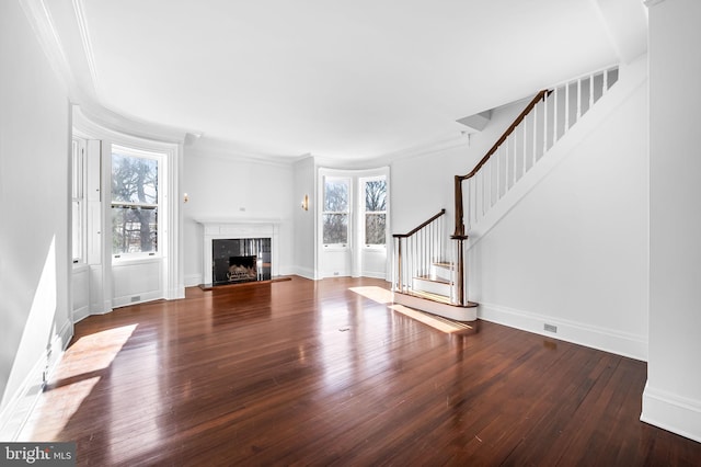 unfurnished living room featuring dark wood-type flooring, a high end fireplace, and ornamental molding