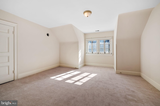 bonus room with vaulted ceiling and light carpet