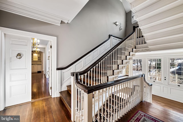 stairs featuring hardwood / wood-style flooring, crown molding, and a notable chandelier