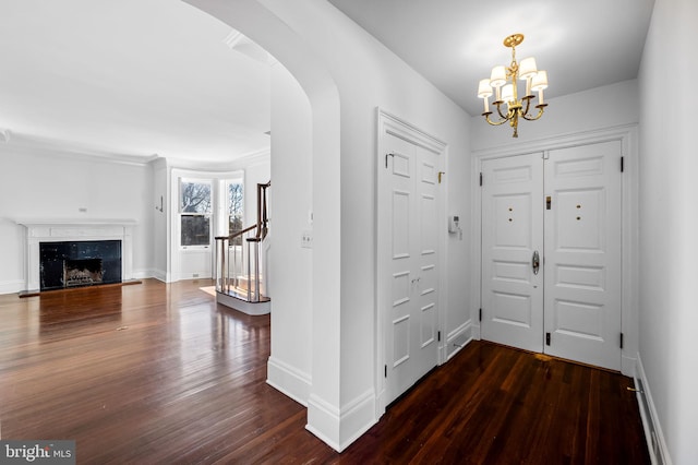 entrance foyer featuring dark wood-type flooring, a high end fireplace, and a chandelier