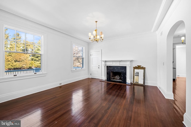 unfurnished living room with crown molding, an inviting chandelier, a premium fireplace, and dark wood-type flooring