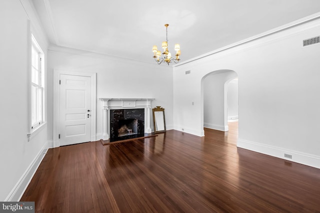 unfurnished living room with dark wood-type flooring, a notable chandelier, a fireplace, and crown molding