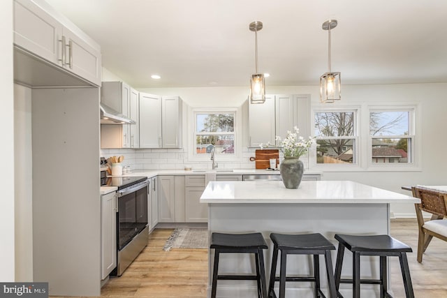 kitchen with backsplash, electric range, decorative light fixtures, and a center island