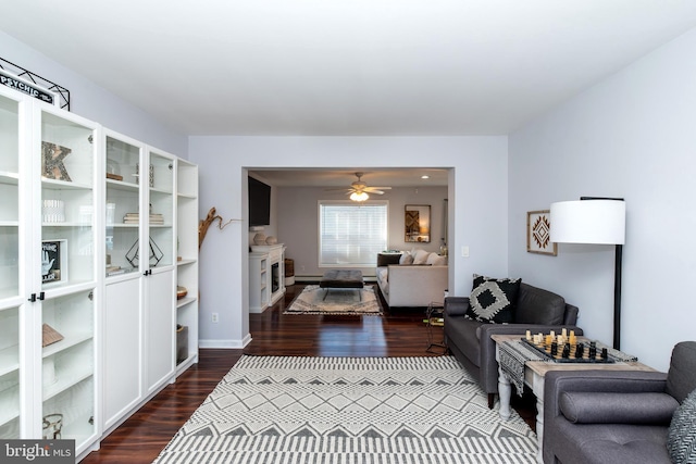 living room featuring ceiling fan and dark hardwood / wood-style floors