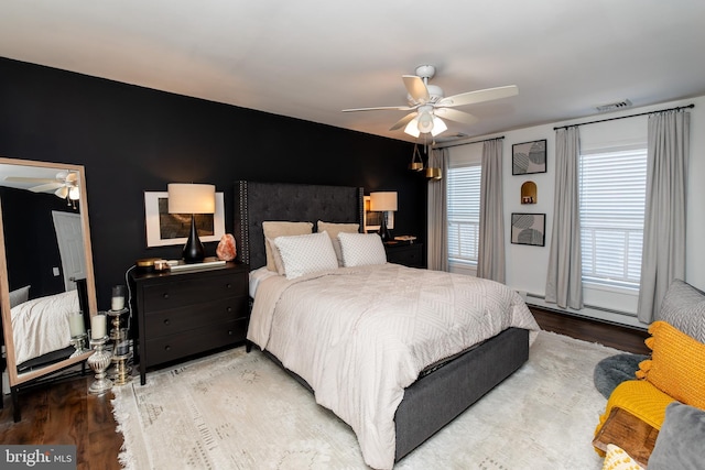 bedroom with a baseboard heating unit, hardwood / wood-style floors, and ceiling fan