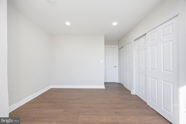 unfurnished bedroom with dark hardwood / wood-style flooring and two closets