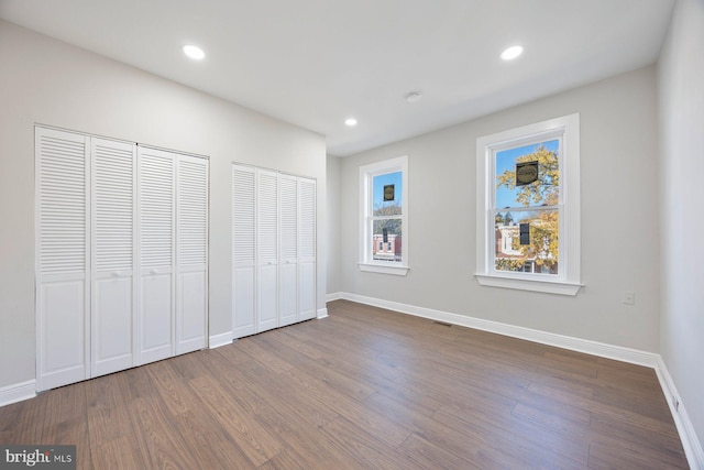 unfurnished bedroom with hardwood / wood-style floors and two closets