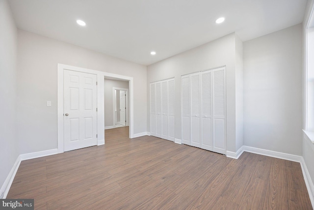 unfurnished bedroom with multiple closets and hardwood / wood-style floors