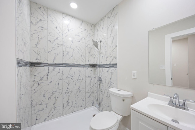 bathroom with tiled shower, vanity, and toilet