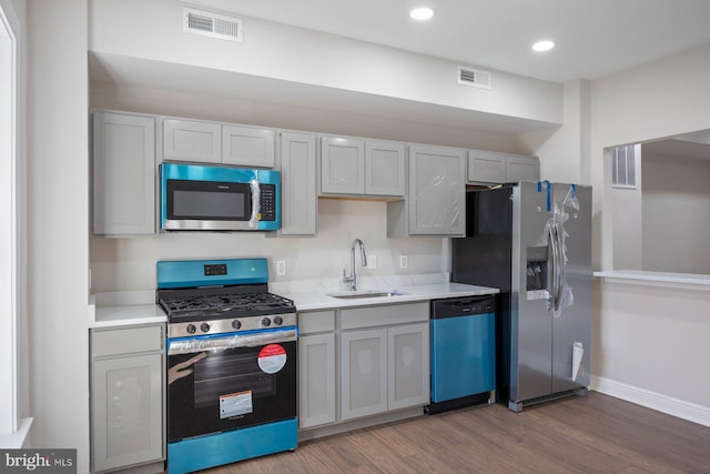 kitchen with gray cabinets, appliances with stainless steel finishes, sink, and dark wood-type flooring