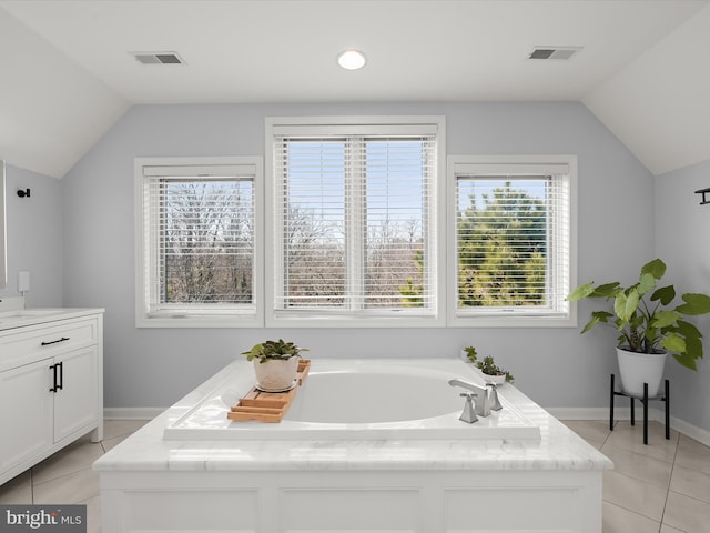 bathroom featuring a washtub, vanity, tile patterned floors, and lofted ceiling