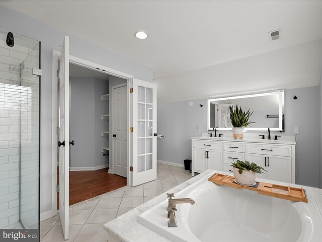 bathroom with tile patterned flooring, vanity, plus walk in shower, and french doors