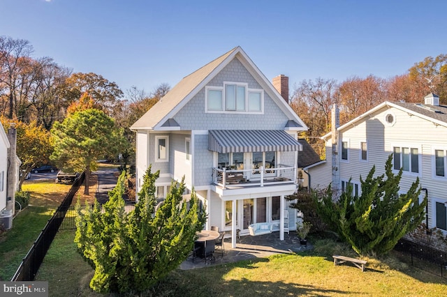 back of house featuring a lawn, a balcony, and a patio area