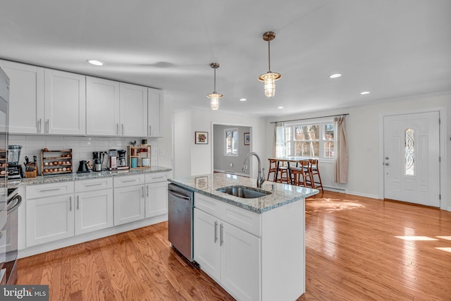 kitchen with pendant lighting, stainless steel dishwasher, sink, and white cabinets