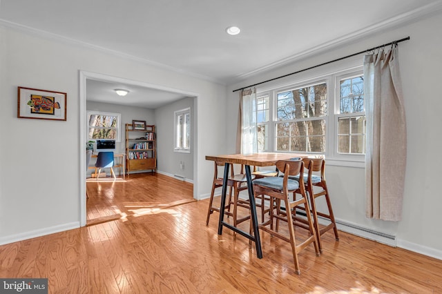 dining space with ornamental molding and light hardwood / wood-style floors