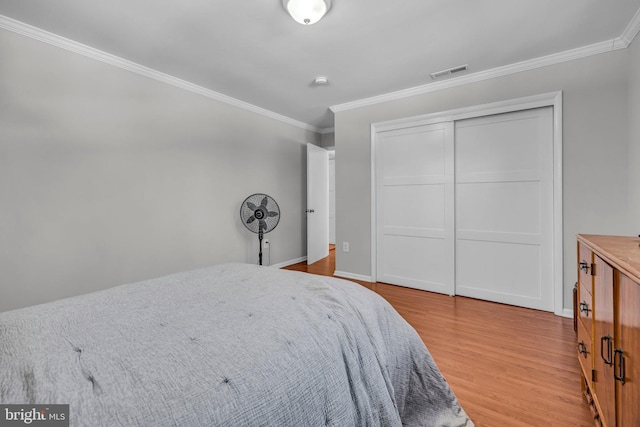 bedroom featuring crown molding, light hardwood / wood-style floors, and a closet