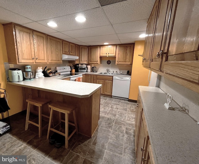 kitchen with sink, white appliances, a breakfast bar, and kitchen peninsula