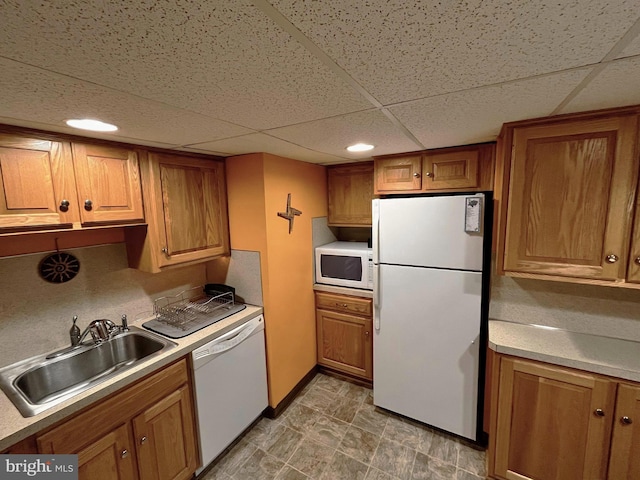 kitchen featuring white appliances, sink, and a drop ceiling