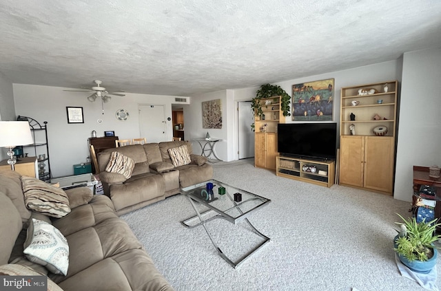 living room featuring ceiling fan, light colored carpet, and a textured ceiling