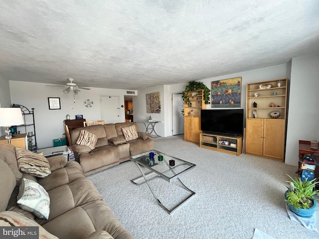 living room featuring ceiling fan, light colored carpet, and a textured ceiling