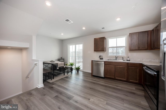 kitchen featuring sink, electric range oven, plenty of natural light, wood-type flooring, and stainless steel dishwasher