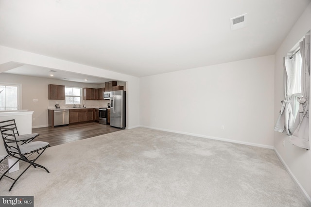 unfurnished living room with light colored carpet and sink