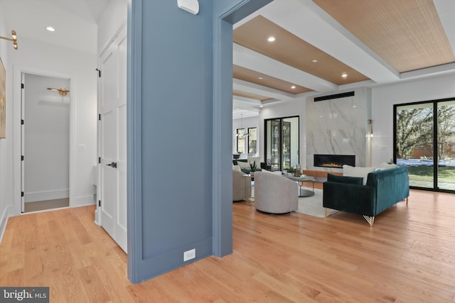 interior space with beam ceiling, a premium fireplace, and light hardwood / wood-style floors