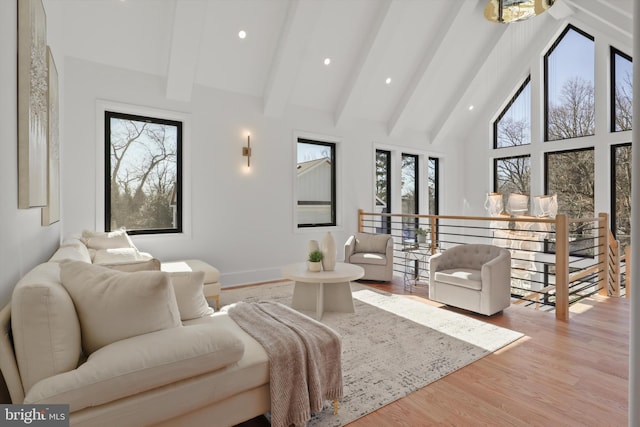 living room with beamed ceiling, light wood-type flooring, and high vaulted ceiling