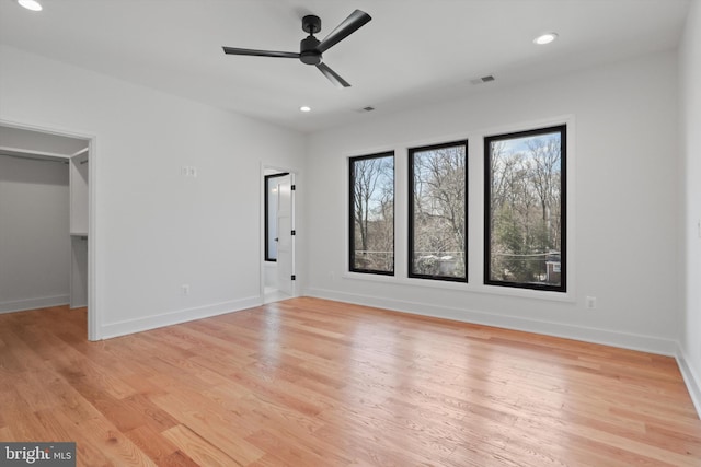 interior space with ceiling fan, a walk in closet, and light wood-type flooring