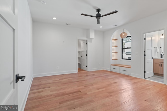 unfurnished bedroom featuring connected bathroom, a spacious closet, and light wood-type flooring