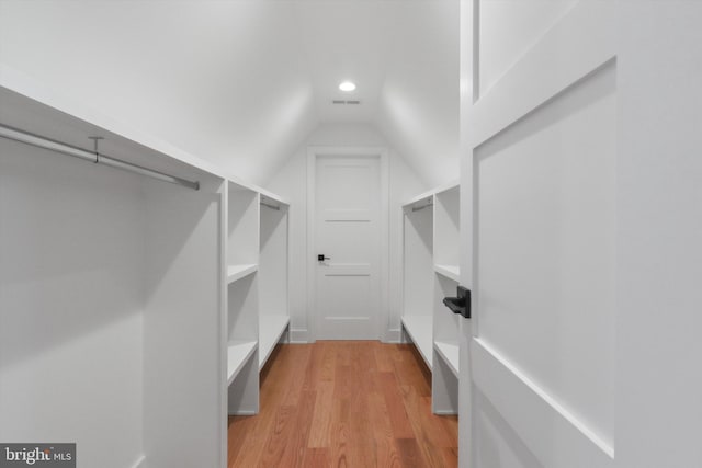 walk in closet with light hardwood / wood-style flooring and vaulted ceiling