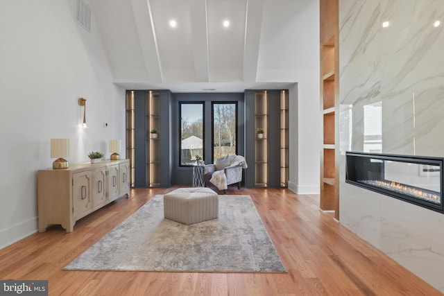 living area with built in features, beam ceiling, light hardwood / wood-style floors, and a tile fireplace