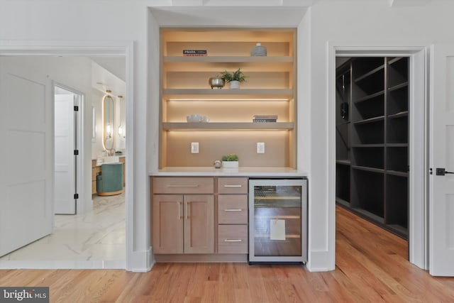 bar featuring wine cooler, built in shelves, and light wood-type flooring