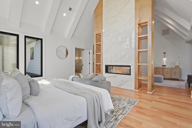 bedroom featuring high vaulted ceiling, a fireplace, beamed ceiling, wood-type flooring, and access to outside