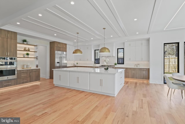 kitchen featuring white cabinetry, appliances with stainless steel finishes, a large island, and pendant lighting