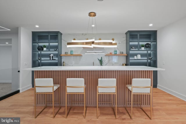 kitchen featuring a breakfast bar, pendant lighting, tasteful backsplash, a center island, and light hardwood / wood-style flooring