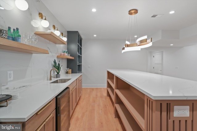 kitchen featuring decorative light fixtures, sink, wine cooler, light hardwood / wood-style floors, and light stone counters