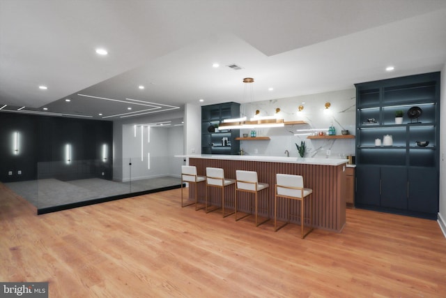 kitchen with pendant lighting, a center island, a breakfast bar, and light hardwood / wood-style flooring