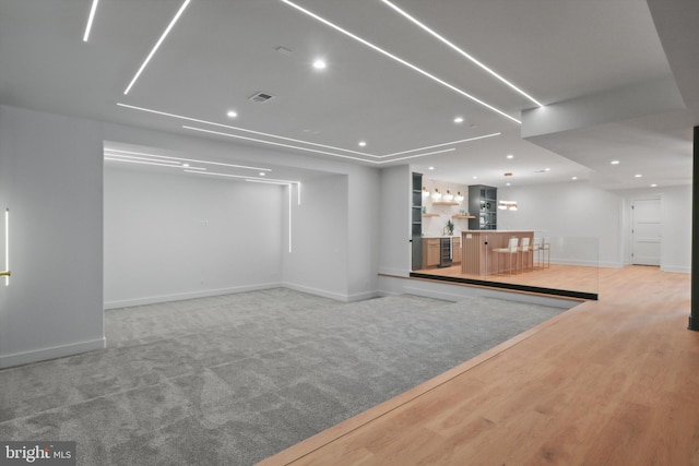 unfurnished living room featuring bar and light wood-type flooring