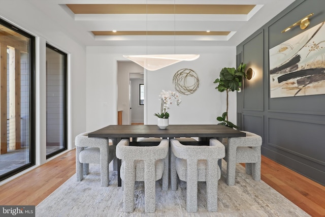 dining space featuring a tray ceiling and light hardwood / wood-style flooring