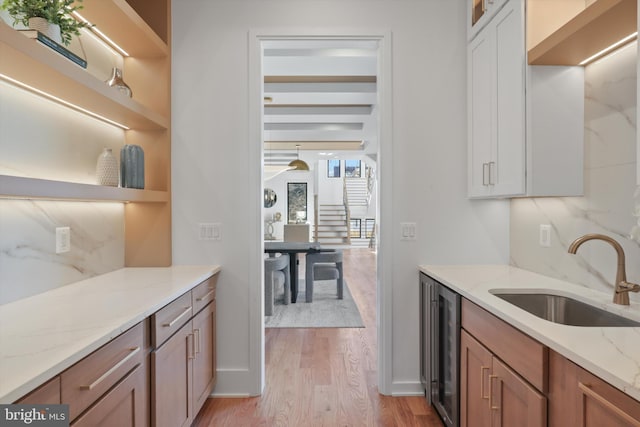 kitchen featuring white cabinetry, sink, wine cooler, and light stone countertops