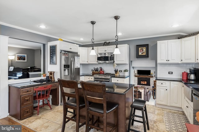 kitchen featuring stainless steel appliances, decorative light fixtures, a breakfast bar area, and white cabinets