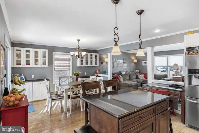 kitchen with decorative light fixtures, stainless steel fridge, white cabinets, and a kitchen island