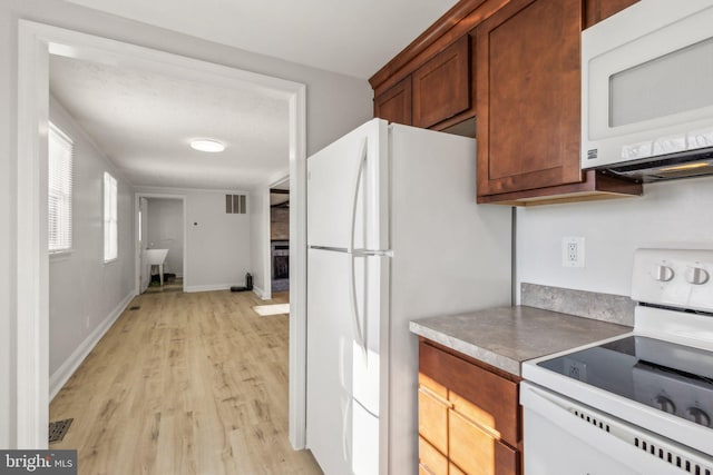 kitchen with white appliances and light hardwood / wood-style floors