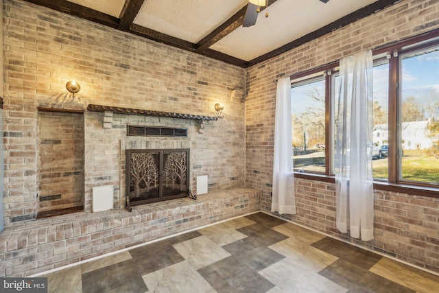 interior space with brick wall, ceiling fan, a brick fireplace, and beam ceiling