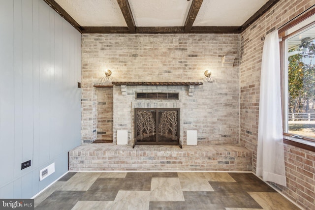 unfurnished living room with beamed ceiling, brick wall, and a wealth of natural light