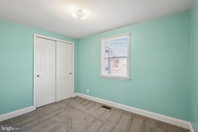 unfurnished bedroom with light carpet and a closet