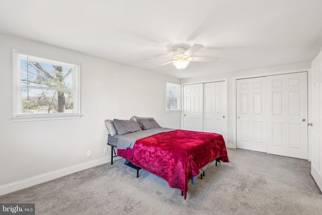 bedroom featuring two closets, light colored carpet, and ceiling fan